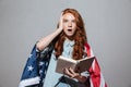 Shocked redhead young lady reading book wearing USA flag Royalty Free Stock Photo