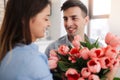 Picture showing man giving flowers to a woman at home. Romantic concept. Woman`s day