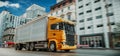 This picture shows a large yellow truck driving on a city road