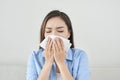 Picture of a sick young lady sitting on the couch and blowing he