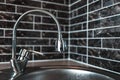 Picture of silver faucet in kitchen area, on the background of dark brick wall. Royalty Free Stock Photo