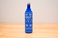 Picture of Skyy Vodka blue bottle in a sweater on a wooden table with grey wall.