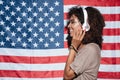 Smiling african young woman standing over USA flag listening mus Royalty Free Stock Photo