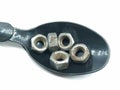 A picture of stainless steel bolts on black spoon ,