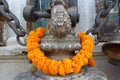 Statue with a garland made with orange flowers at the Boudhanath Stupa, Kathmandu, Nepal Royalty Free Stock Photo