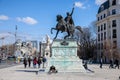 Student with a smartphone sitting under the statue of Mihai the brave (mihai viteazul) on