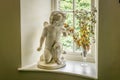 A picture of a statue ornament of a cherub that seems to be smelling some flowers in a vase
