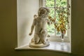 A picture of a statue ornament of a cherub that seems to be smelling some flowers in a vase