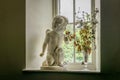 A view of a statue ornament of a cherub that seems to be smelling some flowers in a vase