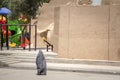Shape of a woman walking in the streets of Yazd, Iran, passing near a children playground, wearing a niqab