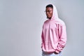 A picture of a stylish african-american man dressed in a pink hoodie with a hood on was taken in the studio on a light red Royalty Free Stock Photo