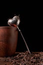 Picture of the tea strainer with dried tea leaves and sticks of cinnamon on dark wooden background