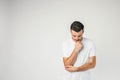 A picture of thoughtful and serious dark-haired man standing on the right side of frame and thinking. He has put his Royalty Free Stock Photo