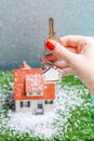 Picture of toy house with falling snow and hands with key Royalty Free Stock Photo