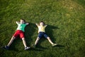 Picture of two brother having fun in the park  two cheerful children laying down on green grass  little boy and his friend playing Royalty Free Stock Photo