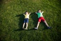 Picture of two brother having fun in the park, two cheerful children laying down on green grass, little boy and his friend playing Royalty Free Stock Photo