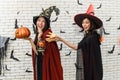 Picture of two emotional young women wearing witch halloween costumes on party over background decorated for Halloween Royalty Free Stock Photo