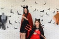 Picture of two emotional young women wearing witch halloween costumes on party over background decorated for Halloween Royalty Free Stock Photo