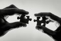 In the picture, two hands, one adult and the other smaller, belonging to a child or teenager, hold puzzle pieces Royalty Free Stock Photo