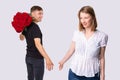The picture of two people, courier man holding the bouquet of wonderful red roses for the pretty woman in white blouse.