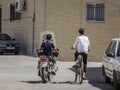 Two young boys, teenagers, riding a motocycle and a bicycle in the streets of the old Kashan, the main city of central Iran