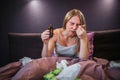 Picture of tyoung woman eating and swallowing spoon of syrup. She shrinks. Woman keeps eyes closed. She holds bottle of Royalty Free Stock Photo