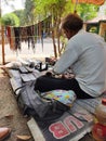 An unknown Shoe Cobler Repairing a Pair of Shoes at Indian Street.