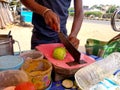 Picture of vendor cutting guava with blade for making chaat with gren chilly paste, red chilli powder, chat masala, salt