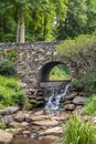 Waterfall under a stone bridge in a park Royalty Free Stock Photo