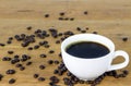 Picture of a white ceramic cup of hot americano coffee on a wooden table with organic dark brown roasted coffee bean Royalty Free Stock Photo