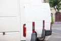 Selective blur on the back light of White delivery vans, parked in row, belonging to a logistics carrier ready for parcel delivery