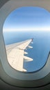 Picture of the window of an airplane from which you can see a wing, the sky and the clouds Royalty Free Stock Photo