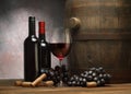 Picture with wine bottles, wineglass of red wine, wooden old barrel and dark grape Royalty Free Stock Photo