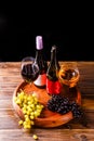 Picture of wine glass with wine, grape black, green on wooden tray on table