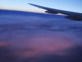 Wing of an airplane going over the clouds at sunset Royalty Free Stock Photo
