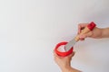 Woman holding putty wall with a spatula on white background. Human hands with putty knife smearing white paste