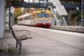 Picture of wooden bench on the train station with blurred train on the background Royalty Free Stock Photo