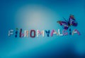 The word Fibromyalgia written by colorful medicines, pills, drugs, tablets, capsules with purple butterfly on a blue background