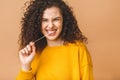 Picture of a young attractive lady dressed in casual standing isolated over beige background stretching bubble gum. Look at camera Royalty Free Stock Photo