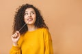 Picture of a young attractive lady dressed in casual standing isolated over beige background stretching bubble gum. Look at camera Royalty Free Stock Photo