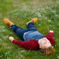 Picture of young beautiful blond man laying on green grass among