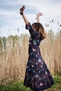 Picture of young blond woman, wearing dark boho dress dancing in front of dry yellow grass in field. Hippie musician relaxing in Royalty Free Stock Photo