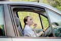 Picture of young businesswoman doing makeup while driving a car in the traffic jam