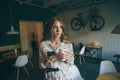 Picture of young cute blonde girl with a cup of coffee holding phone and typing text, beautiful yong woman with bright Royalty Free Stock Photo