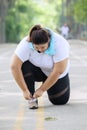 Young fat woman ties her shoelaces before exercising