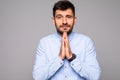 Picture of young guy dressed casually having put hands together in prayer or meditation, looking relaxed and calm, dreaming and