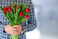 Picture of young man surprising woman with flowers.