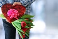 Picture of young man surprising woman with flowers.