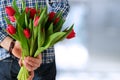 Picture of young man surprising woman with flowers.