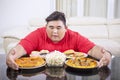 Obese man embracing lots of unhealthy food